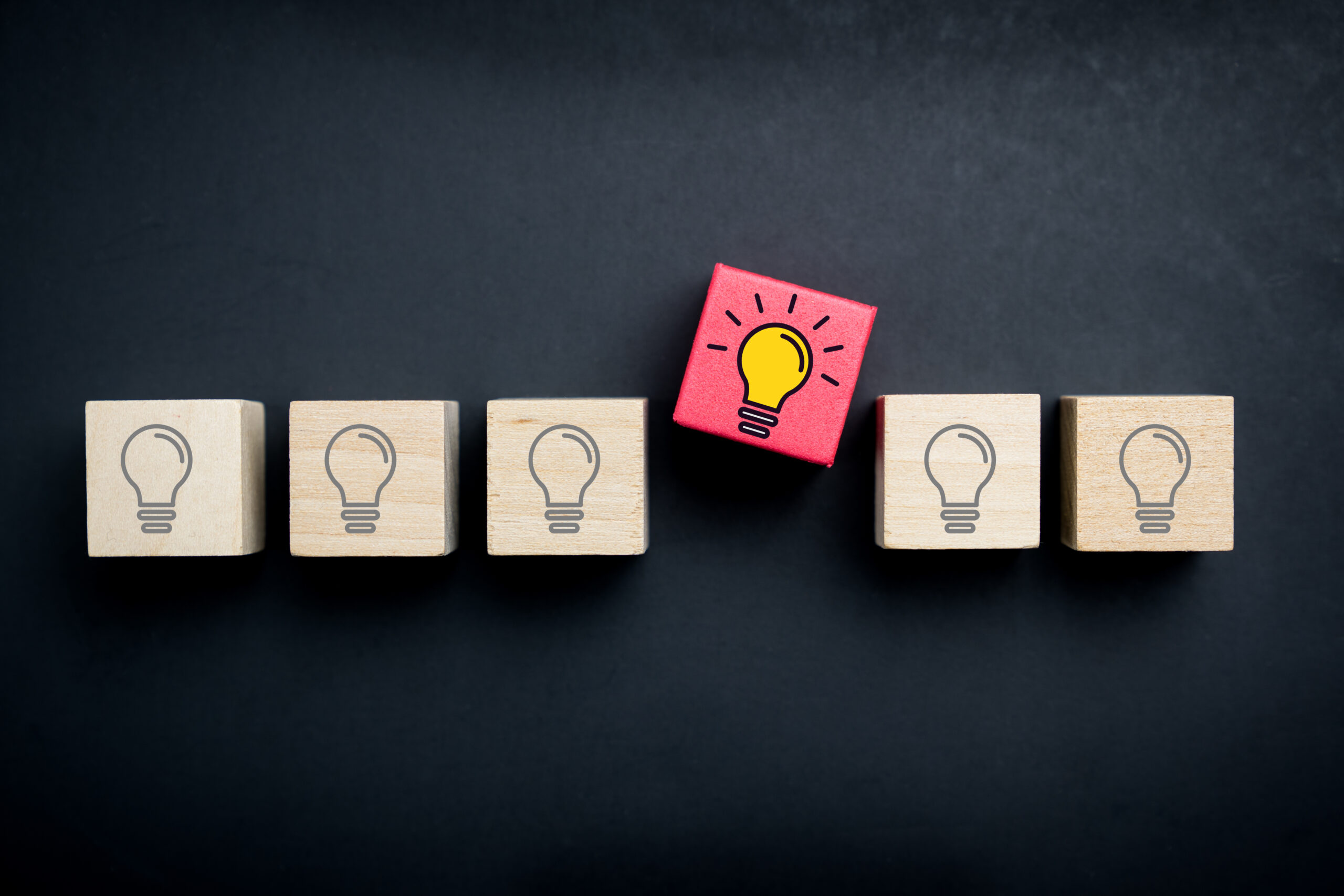 blocks with lightbulbs on them with one that stands out from the rest to conceptualize creativity and innovation